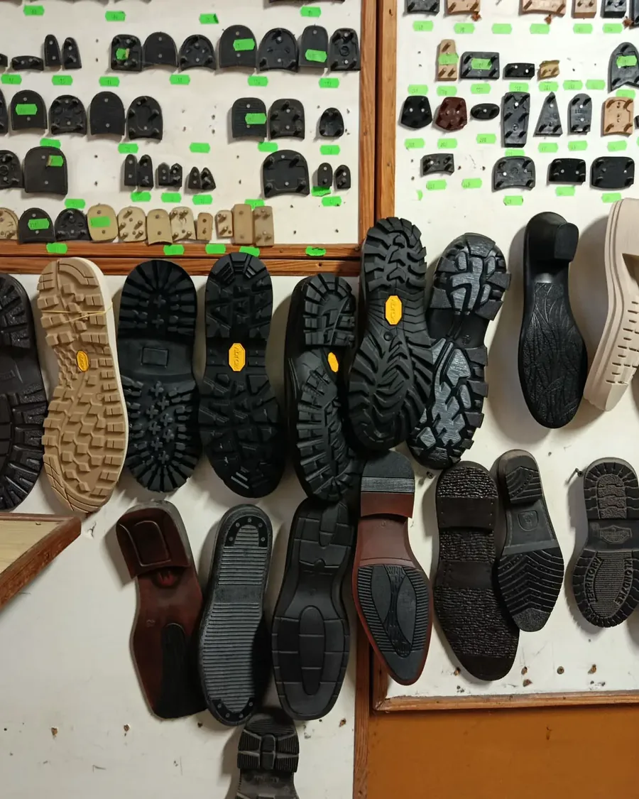 Ściana warsztatu z podeszwami Vibram, flekami i obcasami w różnych rozmiarach